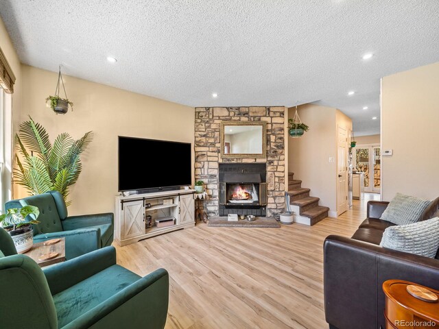 1247 S Idalia St, Aurora, CO 80017 - living room with a stone fireplace, wood finished floors, a textured ceiling, recessed lighting, and stairs