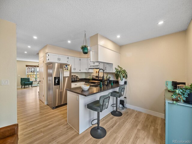 1247 S Idalia St, Aurora, CO 80017 - kitchen with appliances with stainless steel finishes, a peninsula, dark countertops, light wood-style floors, and a breakfast bar