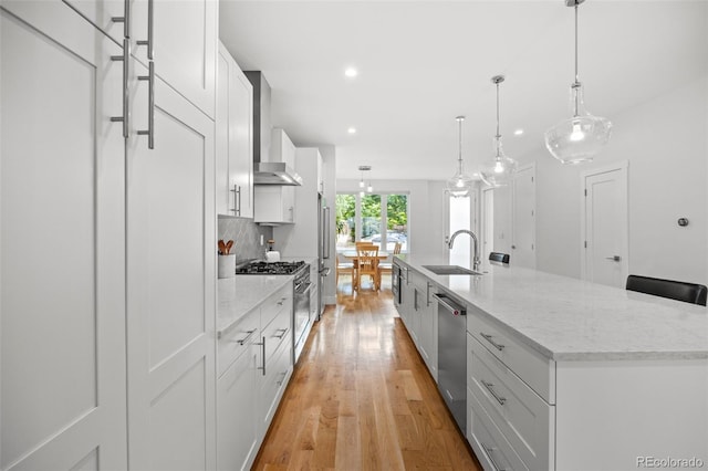 kitchen with white cabinetry, premium appliances, sink, and a large island with sink