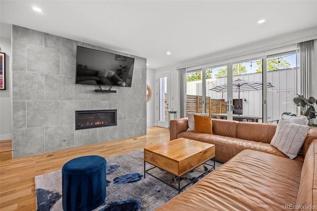 living room with hardwood / wood-style flooring, a tile fireplace, and a healthy amount of sunlight