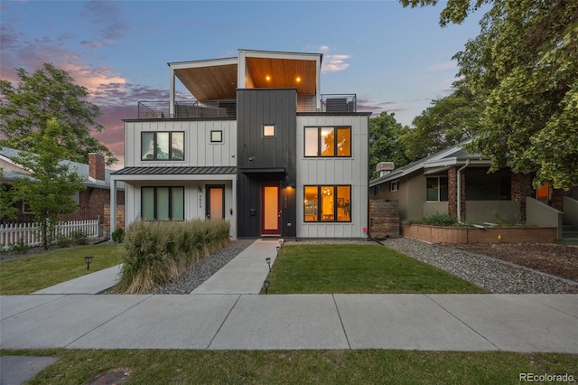 contemporary home with a balcony and a lawn