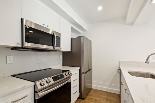 kitchen with white cabinetry, sink, light hardwood / wood-style flooring, and appliances with stainless steel finishes