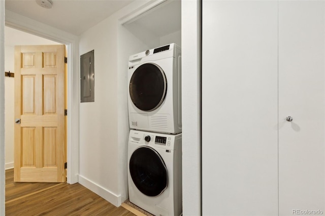 washroom with stacked washer and dryer, hardwood / wood-style flooring, and electric panel