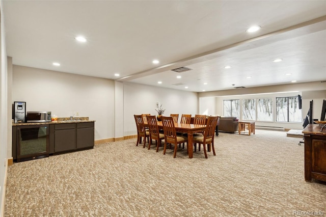 carpeted dining room with baseboard heating and sink