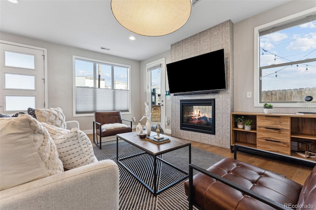 living area with baseboards, visible vents, a tile fireplace, wood finished floors, and recessed lighting