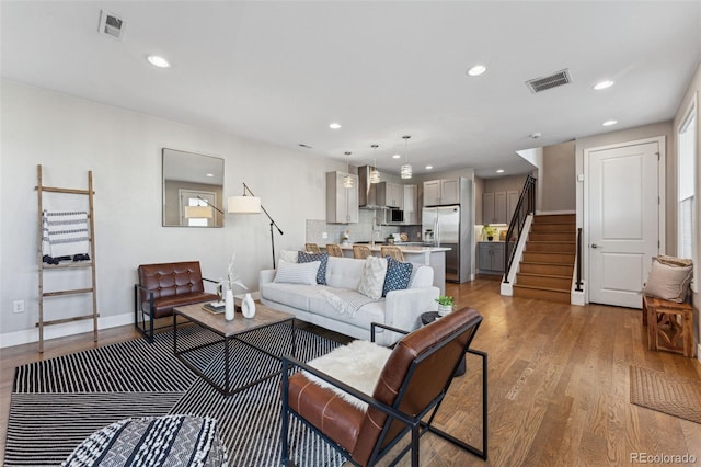 living room featuring recessed lighting, visible vents, stairway, and wood finished floors