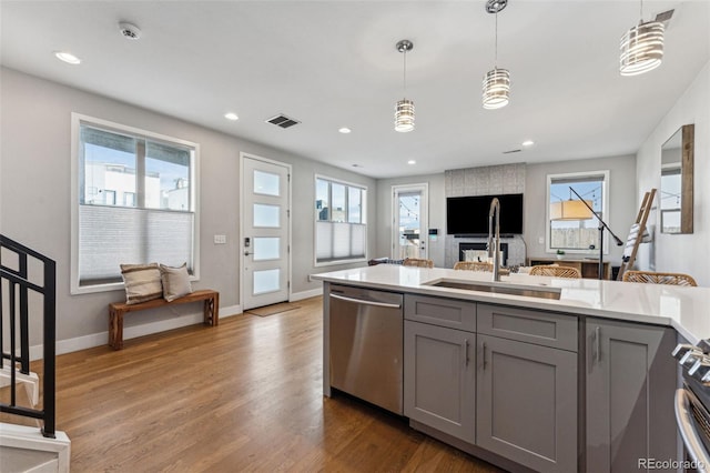 kitchen with pendant lighting, stainless steel appliances, light countertops, visible vents, and gray cabinetry