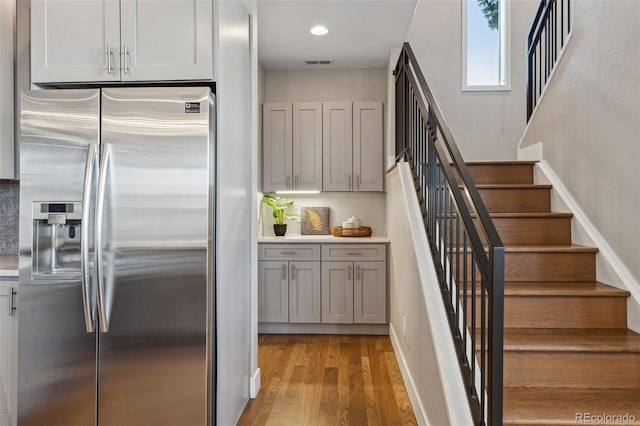 kitchen featuring light wood-style flooring, recessed lighting, visible vents, baseboards, and stainless steel fridge with ice dispenser