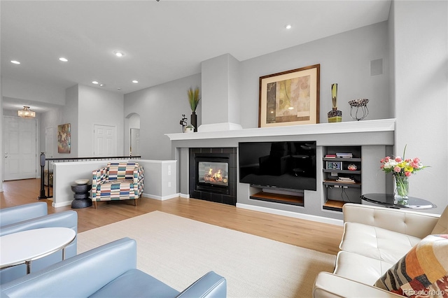1033 Bramblewood Dr, Castle Pines, CO 80108 - living area featuring wood finished floors, arched walkways, recessed lighting, and a tiled fireplace