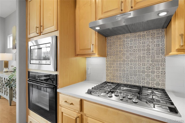 1033 Bramblewood Dr, Castle Pines, CO 80108 - kitchen featuring appliances with stainless steel finishes, under cabinet range hood, tasteful backsplash, light countertops, and wood finished floors