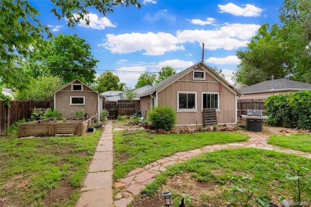 4210 S Fox St, Englewood, CO 80110 - rear view of house with a vegetable garden, board and batten siding, and an outbuilding