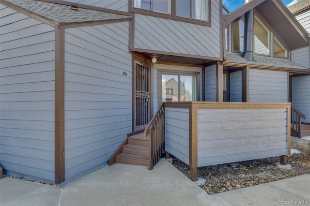 entrance to property featuring a shingled roof