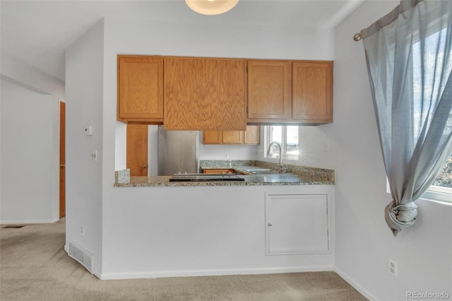 8911 W Yale Ave, Lakewood, CO 80227 - kitchen featuring visible vents, brown cabinetry, freestanding refrigerator, a sink, and baseboards