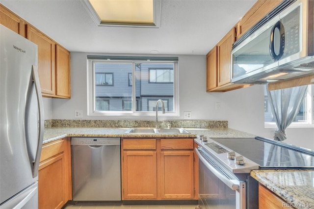 8911 W Yale Ave, Lakewood, CO 80227 - kitchen featuring stainless steel appliances, light stone counters, a sink, and brown cabinets