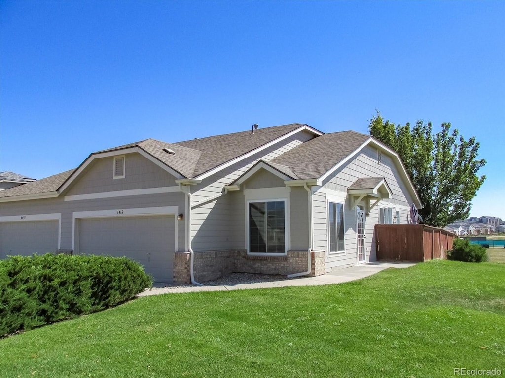 view of front of property featuring a garage, a shingled roof, fence, a front yard, and brick siding