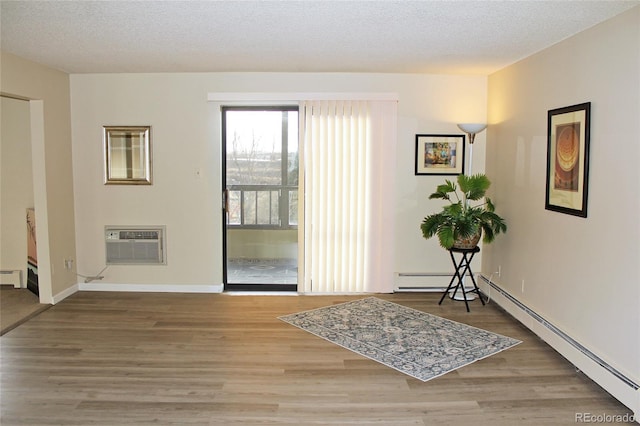 entrance foyer with hardwood / wood-style flooring, a baseboard heating unit, and a textured ceiling