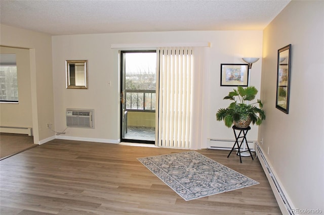 interior space with hardwood / wood-style floors, a textured ceiling, a wall unit AC, and baseboard heating