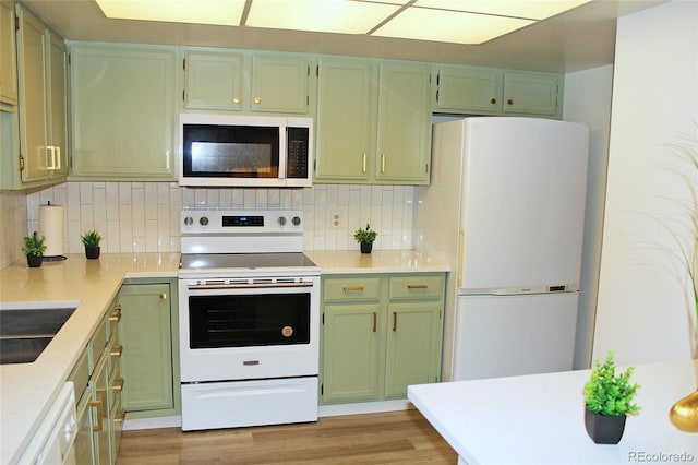 kitchen featuring sink, tasteful backsplash, green cabinetry, white appliances, and light hardwood / wood-style floors