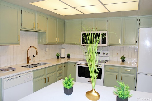 kitchen with tasteful backsplash, white appliances, green cabinets, and sink