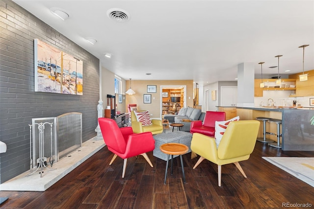 living area with visible vents, a fireplace, brick wall, and wood finished floors