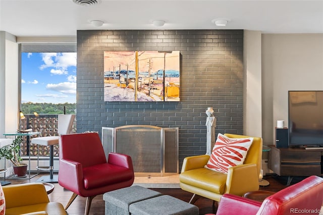 living area featuring a wall of windows, visible vents, wood finished floors, and a fireplace