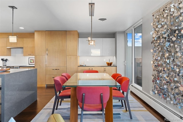 dining room featuring a baseboard heating unit, dark wood finished floors, and visible vents