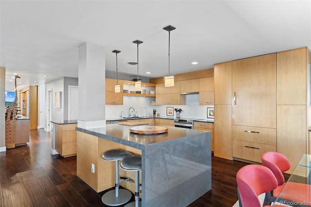 kitchen with a kitchen island, light brown cabinetry, stainless steel range with electric stovetop, dark wood-style floors, and a sink