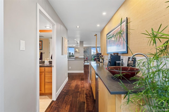 corridor with recessed lighting, baseboards, dark wood-type flooring, and a sink