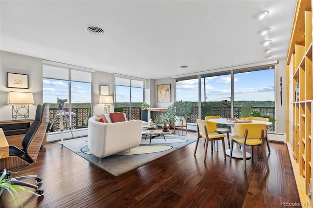 living area featuring a wealth of natural light, visible vents, wood finished floors, and floor to ceiling windows