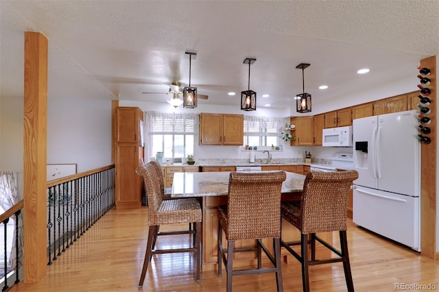 8217 Club Crest Dr, Arvada, CO 80005 - kitchen featuring white appliances, light wood-style flooring, brown cabinetry, a ceiling fan, and pendant lighting