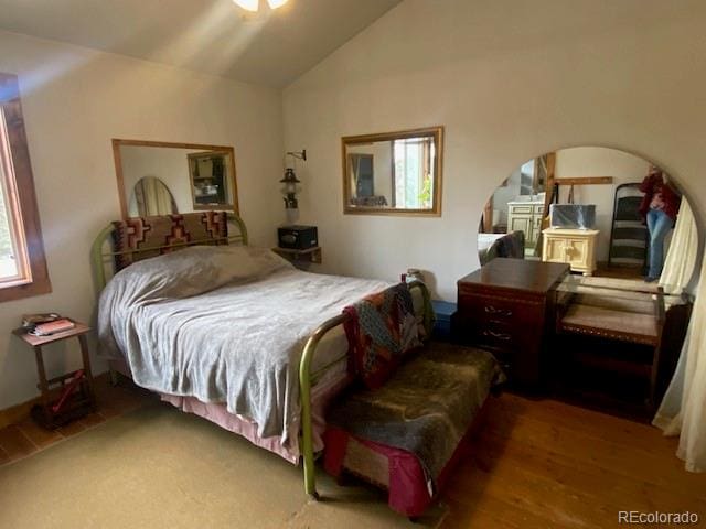 bedroom featuring hardwood / wood-style flooring, vaulted ceiling, and multiple windows