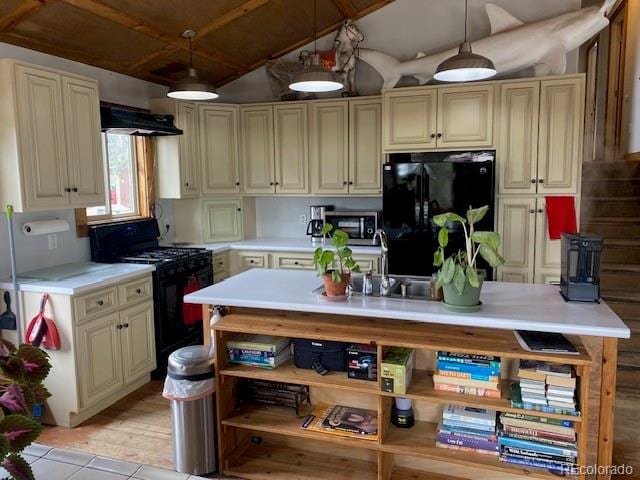 kitchen with decorative light fixtures, exhaust hood, black appliances, and cream cabinets