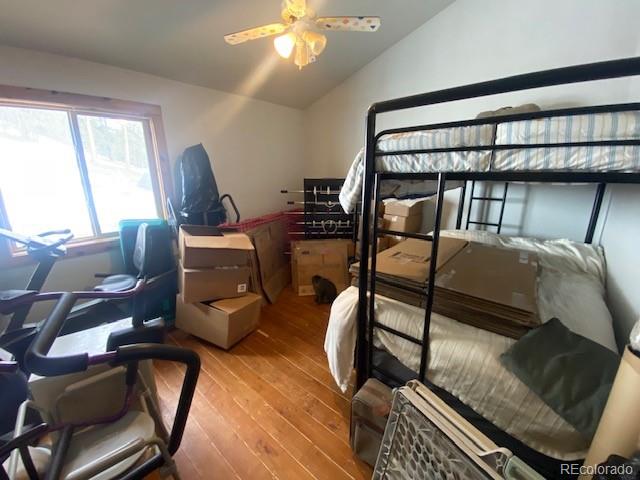 bedroom with ceiling fan, hardwood / wood-style floors, and vaulted ceiling