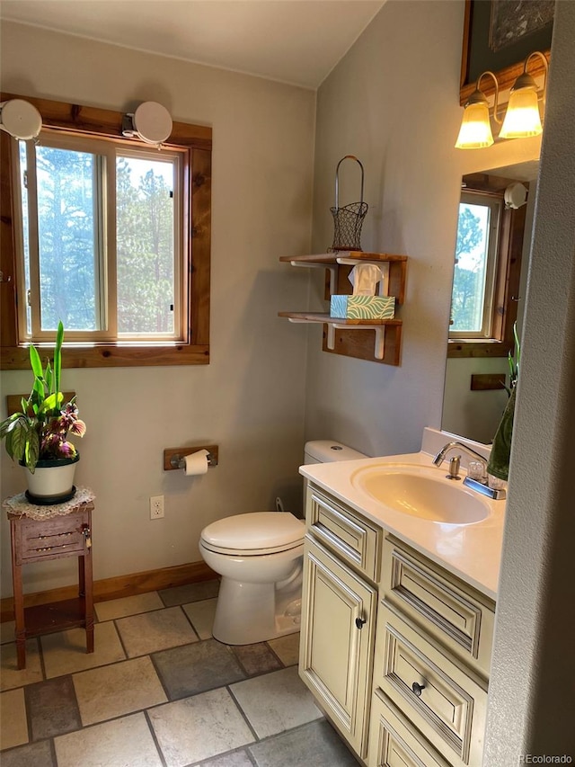 bathroom with toilet, vanity, and a wealth of natural light