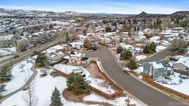 snowy aerial view featuring a mountain view and a residential view