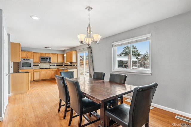 dining area with a notable chandelier, light wood-style flooring, visible vents, and baseboards