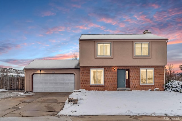 view of front of home with brick siding, fence, stucco siding, a garage, and driveway