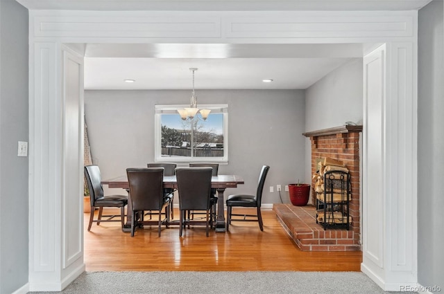 1206 Baldwin Park Cir, Castle Rock, CO 80104 - dining room with a chandelier, wood finished floors, a brick fireplace, baseboards, and recessed lighting