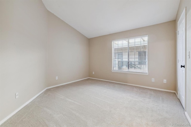 carpeted spare room with vaulted ceiling