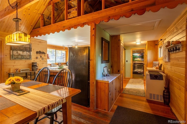 4745 Forest Ln, Howard, CO 81233 - kitchen with freestanding refrigerator, wood walls, hardwood / wood-style floors, heating unit, and brown cabinetry