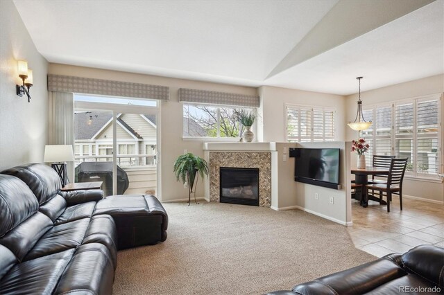 living area featuring a glass covered fireplace, baseboards, lofted ceiling, and a wealth of natural light