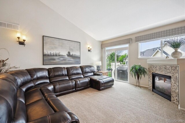 living room with visible vents, lofted ceiling, baseboards, a tiled fireplace, and carpet