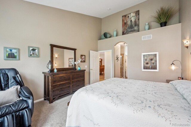 carpeted bedroom featuring visible vents, baseboards, and a high ceiling