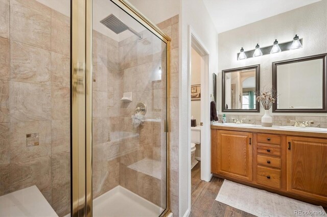 bathroom featuring toilet, a shower stall, a sink, and wood finished floors