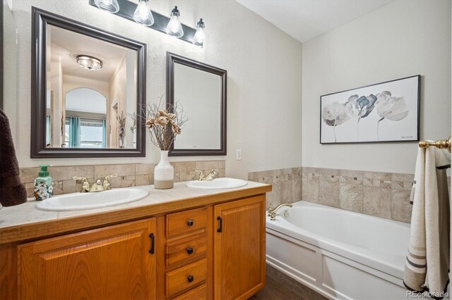 full bath with a sink, a bath, and double vanity