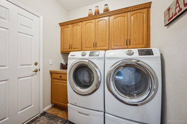 clothes washing area with cabinet space, baseboards, and washing machine and clothes dryer