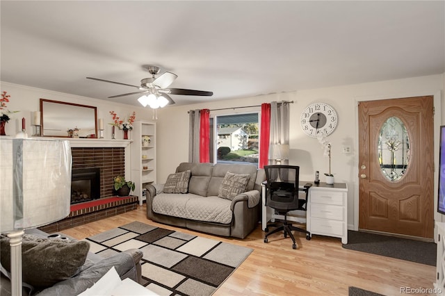 living room with a fireplace, ceiling fan, light wood-type flooring, and ornamental molding