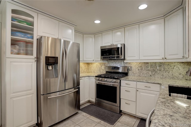 kitchen with light stone countertops, appliances with stainless steel finishes, and white cabinets