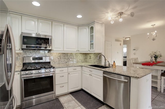 kitchen featuring stainless steel appliances, light stone countertops, sink, white cabinets, and kitchen peninsula