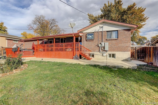 rear view of house with a deck, a lawn, a jacuzzi, and a patio area